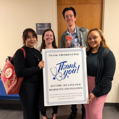 Group photo of residents holding sign and cookies for Thank a Resident and Fellow Day
