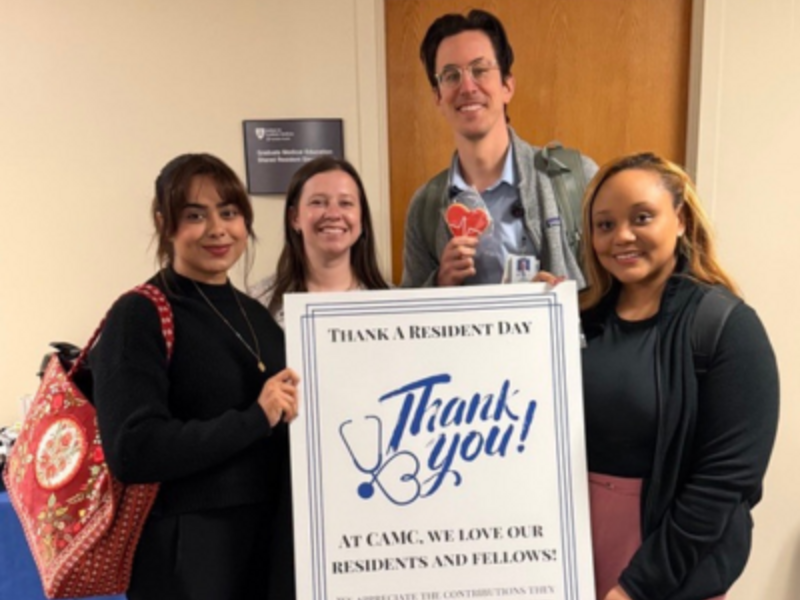 Group photo of residents holding sign and cookies for Thank a Resident and Fellow Day