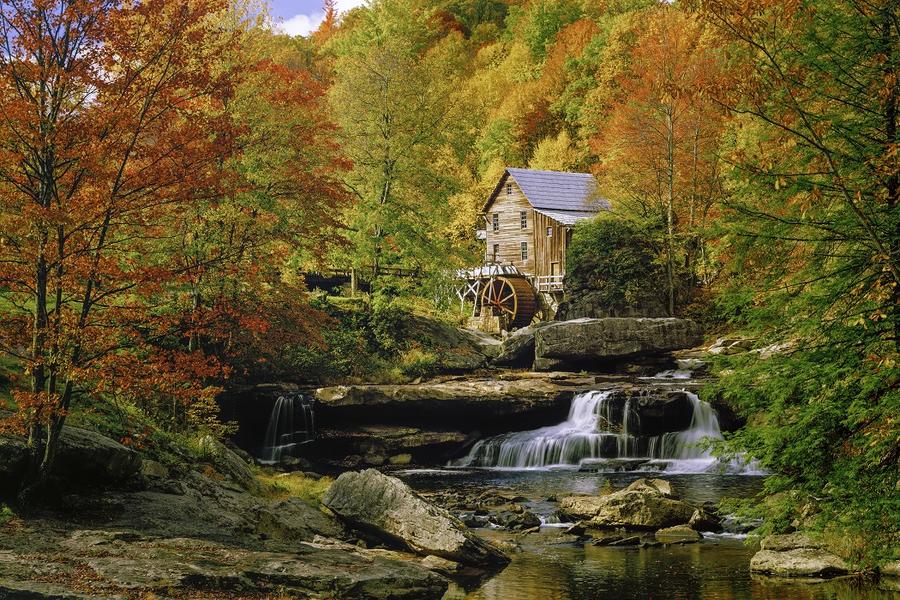 view of a cottage in the fall with a stream and waterful running through it