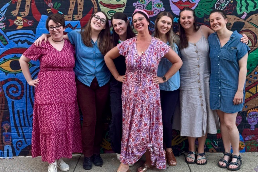 Psychology interns in a group photo in front of art display.
