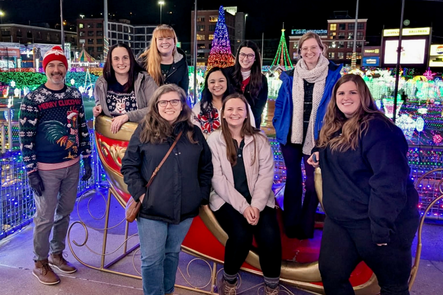 CAMC Psychology interns sit on sleigh for group photo at Light the Night holiday event