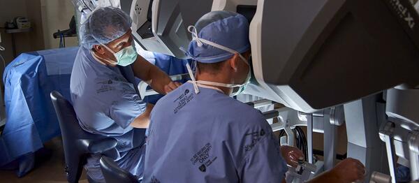 Physician instructing resident on surgical robot