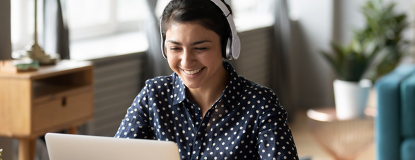 Woman with headphones smiling at laptop