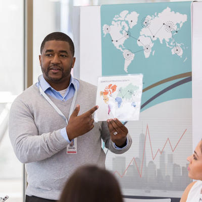 Man making presentation to group as he gestures toward chart