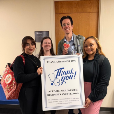 Group photo of residents holding sign and cookies for Thank a Resident and Fellow Day